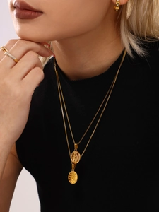 Close-up of double-layered gold stainless steel necklaces with religious pendants