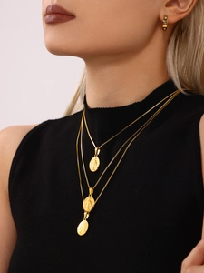 Close-up of triple-layered gold necklaces with classical religious coin pendants