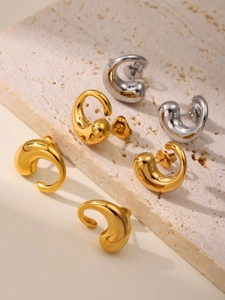 Detailed view of polished curved teardrop earrings in gold and silver finish on stone
