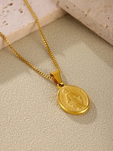 Detailed macro view of gold religious pendant with Miraculous Medal relief and box chain