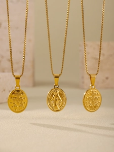 Close-up of gold religious oval medal pendants on box chains against travertine stone
