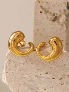 Detail view of gold-plated fluid waterdrop earrings on a textured stone display