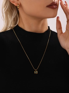 Close-up of gold chain necklace with green square pendant and matching hoop earrings
