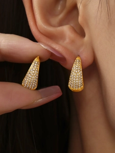 Macro detail of gold teardrop earrings paved with sparkling white cubic zirconia crystals