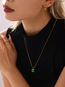 Macro detail of gold-tone necklace with green malachite pendant and diamond accents