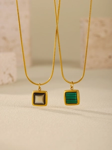 Close-up of gold square pendant necklaces featuring black onyx and green malachite inlays