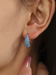 Macro shot of silver teardrop earrings featuring light blue turquoise micro-pavé setting