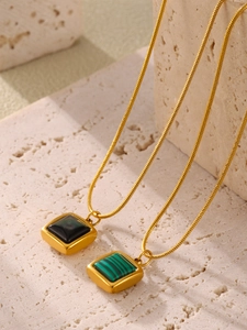 Detail of square gold necklace with black shell and green malachite pendant inlay