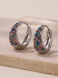 Detailed close-up of hoop earrings with colorful crystals on a beige stone surface