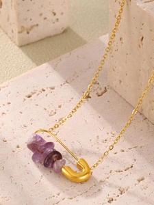 Close-up of golden safety pin pendant with natural purple stones on link chain