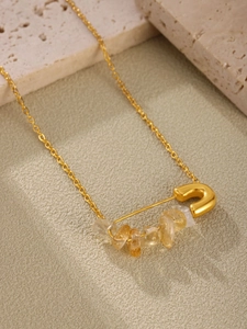 Detail of natural stones on a gold-plated stainless steel safety pin pendant necklace.