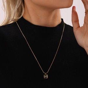 Elegant gold-plated necklace with a square green malachite pendant on a black turtleneck
