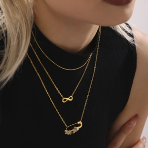 Three-layer gold necklace set featuring infinity and paperclip charms with raw stones