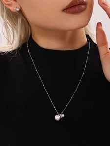 Detailansicht von Perlenkette und Bogenohrringen an einem Modell mit schwarzem Rollkragen
