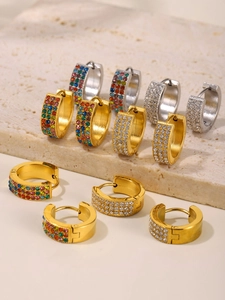Dettaglio di orecchini huggie con zirconi colorati e finiture in oro e argento