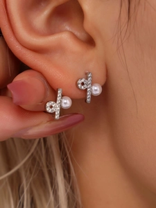 Detail von Silberohrringen mit Zirkonia und Perlen, die elegant am Ohr anliegen