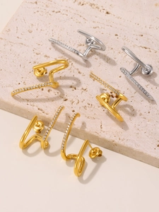Dettaglio di tre paia di ear cuff a spirale con zirconi in finitura oro e argento