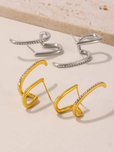 Vista macro di orecchini a curva S in oro e argento con micro-intarsio di zirconi bianchi