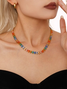 Gros plan d'un collier en acier plaqué or 18 carats avec zircons colorés porté par un mannequin