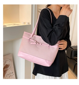 Sac cabas rose tissé avec base en cuir et boucle métallique porté par un mannequin