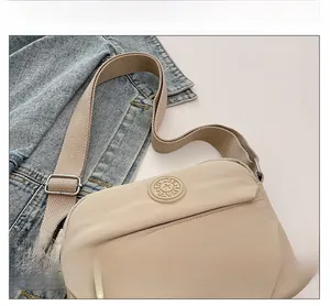 Detail of beige nylon crossbody bag with circular logo and adjustable wide strap