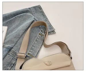 Detail view of the beige nylon crossbody bag with an adjustable wide fabric strap