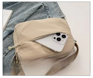 Detail of khaki nylon crossbody bag front zipper pocket for large smartphone storage