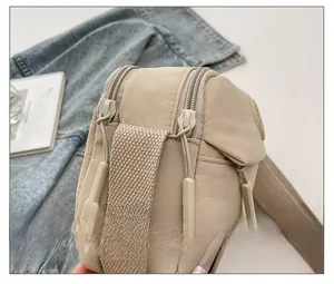 Macro view of smooth double zipper closures on beige nylon crossbody bag