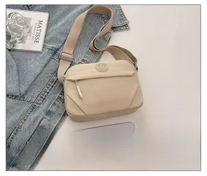 Detail showing beige nylon crossbody bag texture with adjustable strap and zip pocket