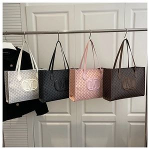 Detailed view of monogrammed tote bags in white, black, pink and dark brown displayed on rack