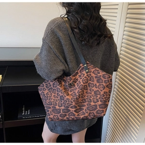 Close-up of leopard print tote bag with metal twist lock worn over the shoulder