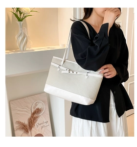 Détail d'un grand sac cabas tissé beige et blanc avec boucle métallique ajustable