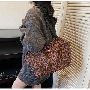 Close-up of leopard print tote bag featuring a golden turn-lock buckle and black strap