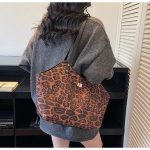 Detail of leopard print tote bag showing black leather shoulder strap and golden buckle