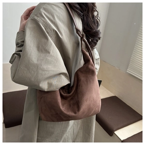 Deep brown suede hobo bag shown in a stylish side-view on a green shirt-wearing model
