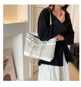 Détail du sac cabas en paille tressée avec bordure en cuir blanc et anses solides