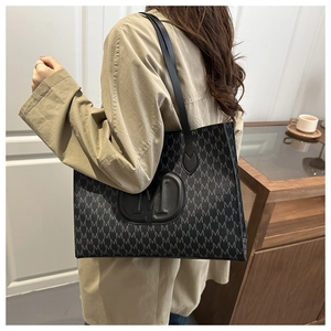 Close-up of black tote bag with M-letter jacquard pattern and textured letter block
