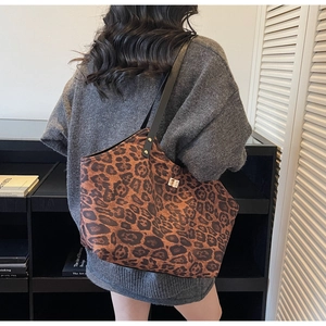 Close-up of leopard print tote bag with black leather straps and golden metal lock