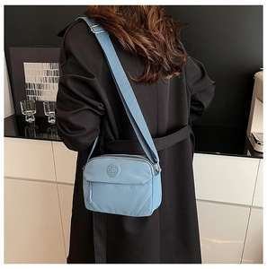 Rear view of a model wearing the blue multi-pocket nylon crossbody bag with adjustable strap
