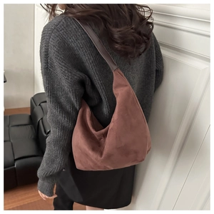 Detail of vintage brown suede hobo bag with dark leather strap shown on shoulder