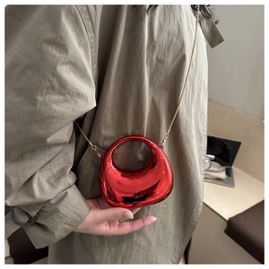 Detail van rode halve maan mini tas met gouden kettingriem gedragen op de schouder