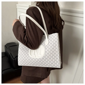 Close-up of a white tote bag with M-letter prints on a model in a brown blazer