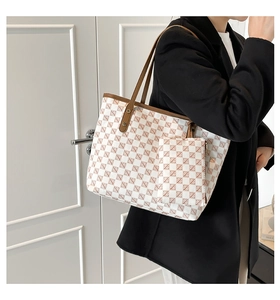 Lifestyle shot of a white patterned tote bag with brown leather straps and small pouch
