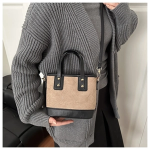 Gros plan du sac seau matelassé marron avec rivets dorés et poignées en cuir