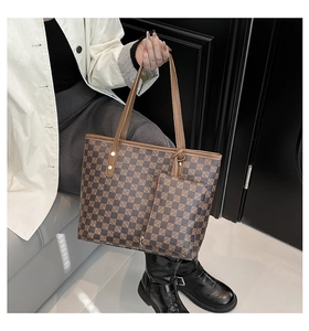 Detail of checkered tote bag with matching pouch and brown leather handles on model