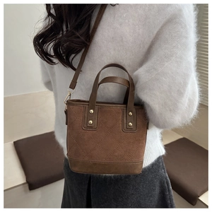 Détail du sac fourre-tout matelassé marron avec empiècements en daim et rivets dorés