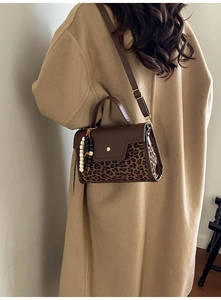 Detail of retro handbag featuring leopard print suede texture and gold metal buckle