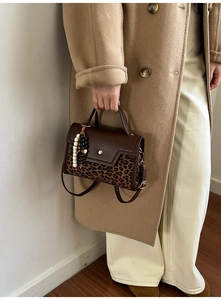 Detail of retro brown leather baguette bag with leopard print and beaded charms on a camel coat