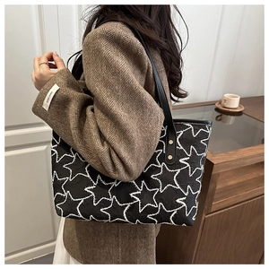 Detail of star embossed tote bag with leather strap and golden rivet reinforcement