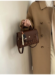 Detail of retro baguette bag with leopard print flap and chic beaded strap ornament